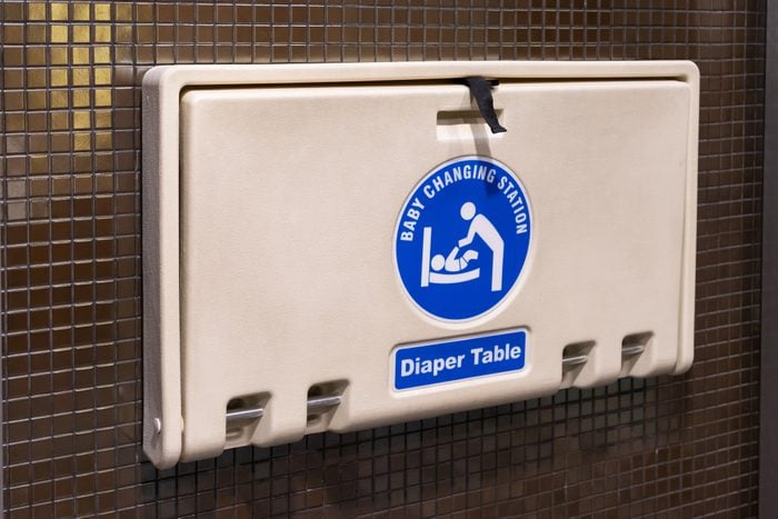 white plastic diaper table on brown ceramic wall in toilet. Baby diaper table in a public restroom