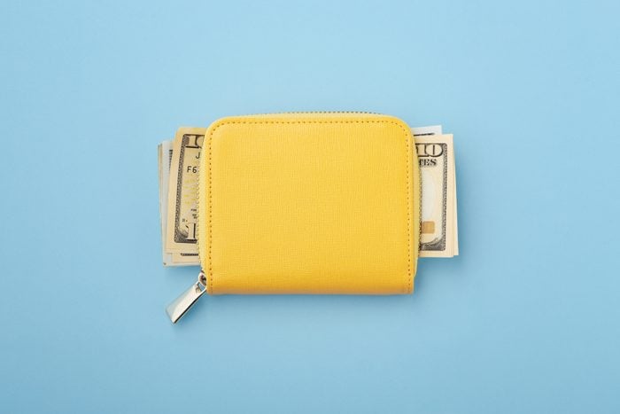 Money in yellow wallet on blue background