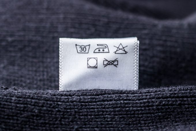 close up of laundry symbols on a care tag of a dark gray wool sweater