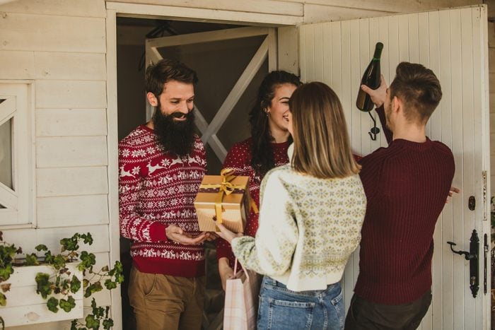 Couple arriving at their friends' house, giving them presents