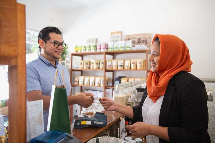 Muslim Female Cashier Accepting Card Payment From a Customer