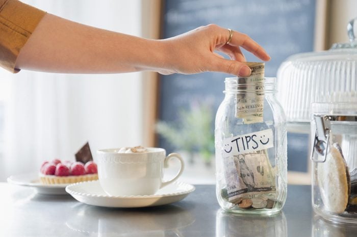Caucasian woman putting money in tip jar