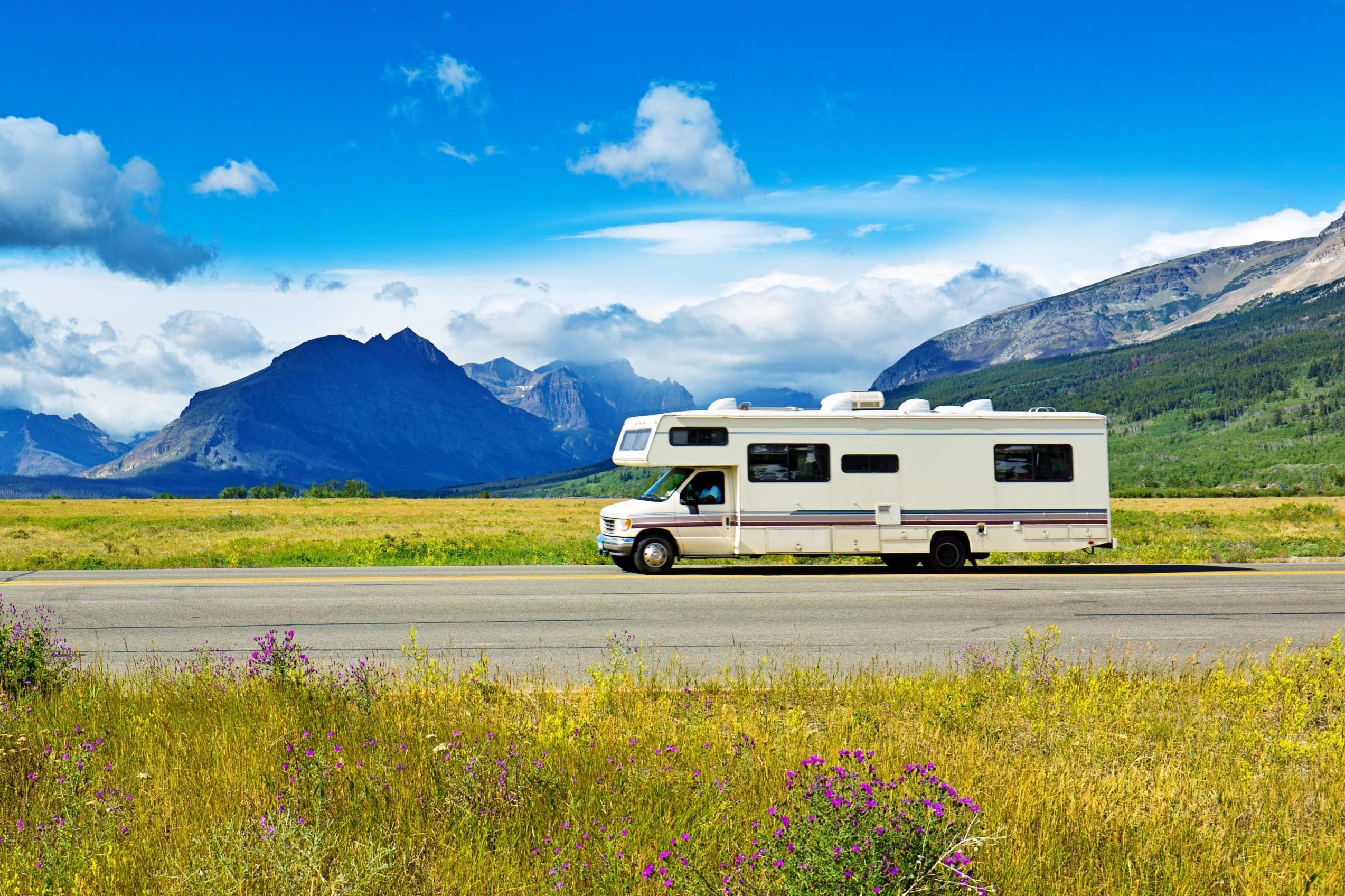 rv on the road among a beautiful landscape with mountains in the background