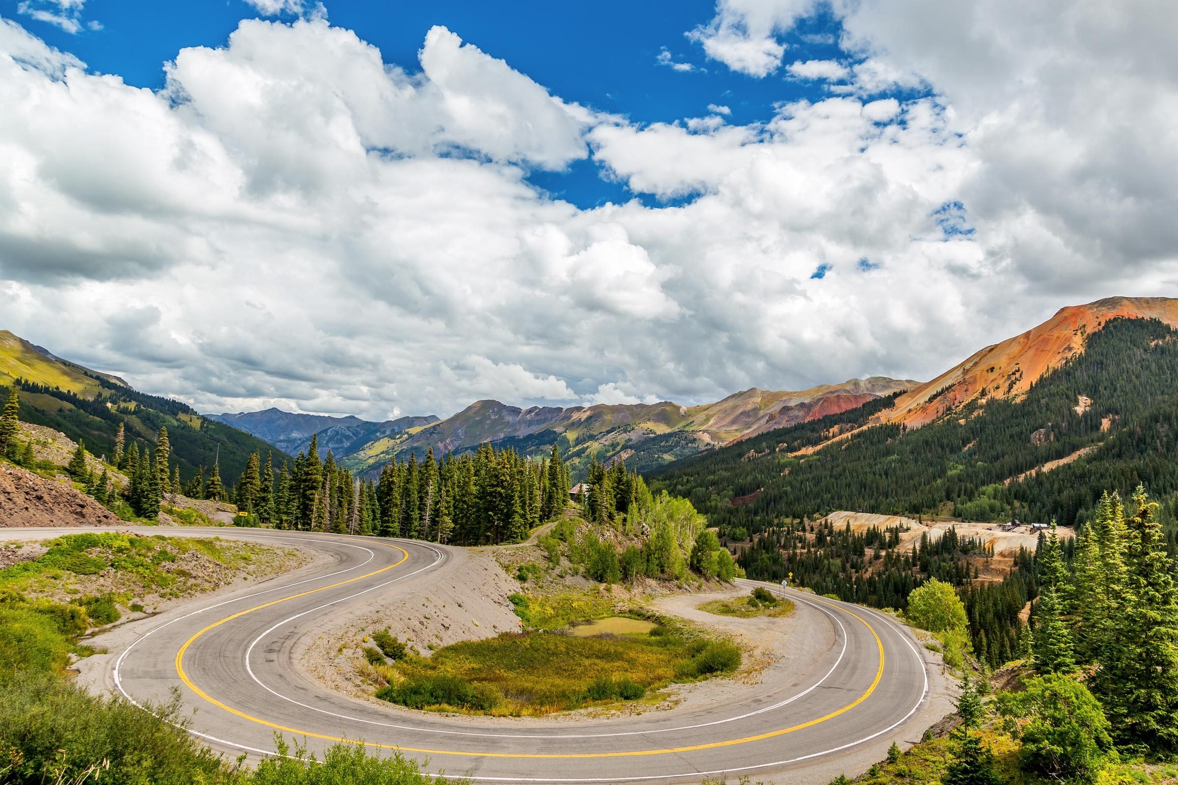 the winding road of the Million Dollar Highway, a piece of the San Juan Skyway in Colorado, with breaktaking views of the San Juan Mountains in the background