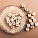 letter tiles on wood slide; brown paper background