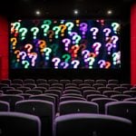 empty movie theatre with a screen of question marks